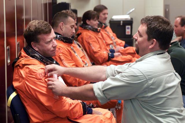 JSC2001-E-06408 (27 February 2001) --- Astronauts (from left foreground) Steven W. Lindsey, commander; Charles O. Hobaugh, pilot; Michael L. Gernhardt, Janet L. Kavandi, and James F. Reilly, all mission specialists, don training versions of the full-pressure launch and entry suit prior to a training session in one of the trainer/mockups (out of frame) in the Johnson Space Center’s Systems Integration Facility. The astronauts are assisted by suit technicians (from right foreground) Len Groce and Drew Billingsley. The STS-104 mission to the International Space Station (ISS) represents the Space Shuttle Atlantis' first flight using a new engine and is targeted for a liftoff no earlier than June 14, 2001.