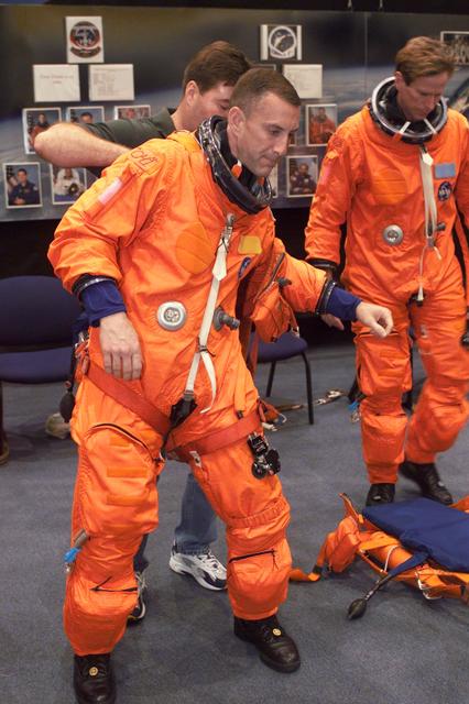 JSC2001-E-06410 (27 February 2001) --- Astronaut Charles O. Hobaugh, pilot, is assisted in his suiting process by suit technician Mike Thompson, and astronaut Michael L. Gernhardt, mission specialist, during mission training at the Johnson Space Center&#0146;s Systems Integration Facility. The STS-104 mission to the International Space Station (ISS) represents the Space Shuttle Atlantis' first flight using a new engine and is targeted for a liftoff no earlier than June 14, 2001.