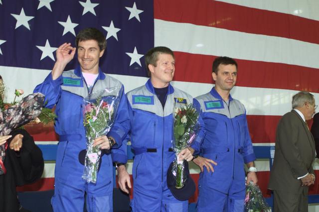 JSC2001-E-08313 (22 March 2001) ---  Astronaut William M. (Bill) Shepherd (center), Expedition One mission commander, is flanked by his two cosmonaut crewmates as they greet a crowd gathered for a crew return ceremony in Ellington Field's Hangar 990.  Yuri P. Gidzenko (right foreground) served as Soyuz commander for the first staffing of the International Space Station (ISS) and  Sergei K. Krikalev (left) was flight engineer.