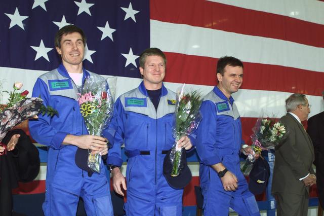 JSC2001-E-08314 (22 March 2001) ---  Astronaut William M. (Bill) Shepherd (center), Expedition One mission commander, is flanked by his two cosmonaut crewmates as they greet a crowd gathered for a crew return ceremony in Ellington Field's Hangar 990.  Yuri P. Gidzenko (right foreground) served as Soyuz commander for the first staffing of the International Space Station (ISS) and  Sergei K. Krikalev (left) was flight engineer.