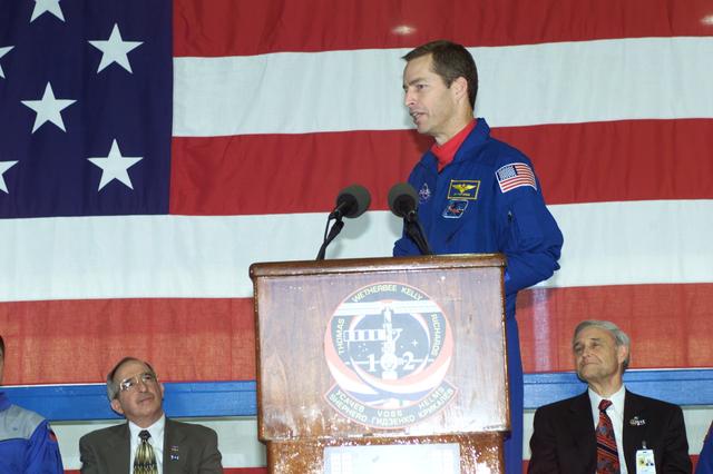 JSC2001-E-08326 (22 March 2001) --- Astronaut James D. Wetherbee, STS-102 mission commander, speaks to a crowd of  greeters during a crew return ceremony in Ellington Field's Hangar 990.  Pictured in the background on the dais are Joseph Rothenberg (left), NASA Associate Administrator for Space Flight, and Roy S. Estess, Johnson Space Center's Acting Director.
