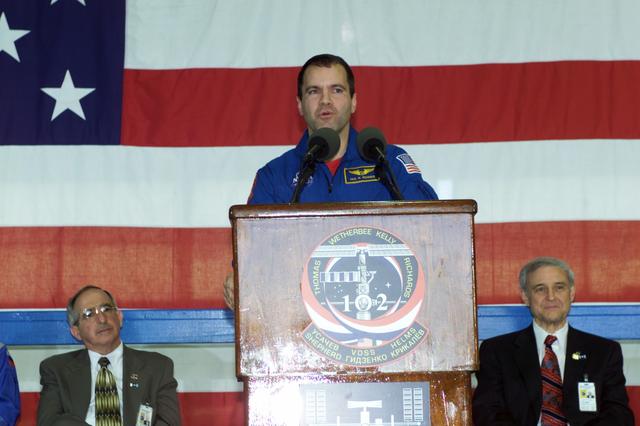 JSC2001-E-08330 (22 March 2001) --- Astronaut Paul W. Richards, STS-102 mission specialist, speaks to a crowd of greeters during a crew return ceremony in Ellington Field's Hangar 990.  Pictured in the background on the dais are Joseph Rothenberg (left), NASA Associate Administrator for Space  Flight, and Roy S. Estess, Johnson Space Center's Acting Director.
