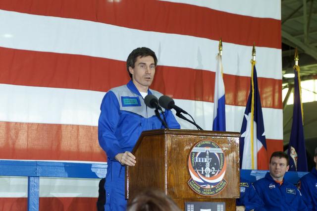 JSC2001-E-08332 (22 March 2001) --- Cosmonaut Sergei K. Krikalev, Expedition One flight engineer, speaks to a crowd of greeters during a crew return ceremony in Ellington Field's Hangar 990.  Pictured in the background on the dais is astronaut James M. Kelly, STS-102 pilot.