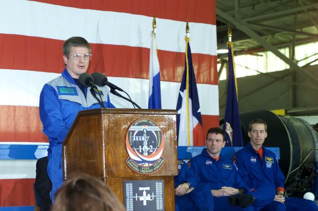 JSC2001-E-08334 (22 March 2001) ---  Astronaut William M. (Bill) Shepherd, Expedition One mission commander, speaks to a crowd of greeters during a crew return ceremony in Ellington Field's Hangar 990.  Pictured in the background on the dais are astronauts James M. Kelly (left), STS-102 pilot, and James D. Wetherbee, commander.