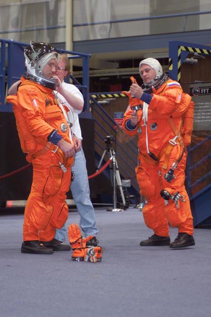 JSC2001-E-18119 (18 May 2001) --- Astronaut Carl E. Walz (left), Expedition Four flight engineer, and cosmonaut Yuri I. Onufrienko, mission commander representing Rosaviakosmos, don their training versions of the full-pressure launch and entry suit prior to a mission training session in the Space Vehicle Mockup Facility at the Johnson Space Center (JSC). Walz and Onufrienko are assisted by United Space Alliance (USA) suit tech Daniel Palmer.