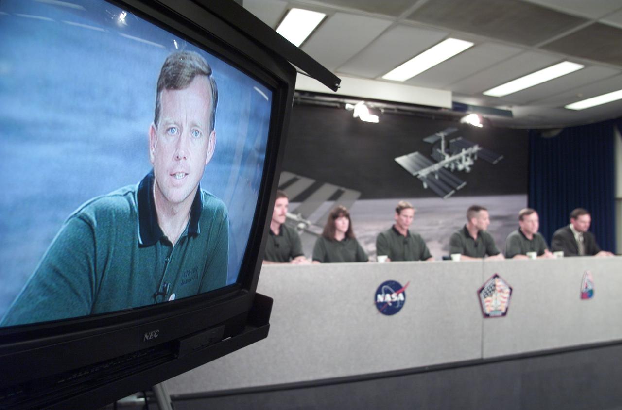 JSC2001-E-19300 (25 June 2001) --- A close-up image of astronaut Steven W. Lindsey, STS-104 mission commander, shows on a nearby television monitor during a pre-flight press conference at Johnson Space Center (JSC). The entire STS-104 crew can be seen in the background, along with moderator Kyle Herring (right).