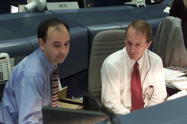 JSC2001-E-21559 (13 July 2001) --- Astronauts Mark L. Polansky (left) and Steven G. MacLean of the Canadian Space Agency (CSA) look over information regarding the STS-104 mission at the spacecraft communicator (CAPCOM) console in the shuttle flight control room (WFCR) in Houston's Mission Control Center (MCC).