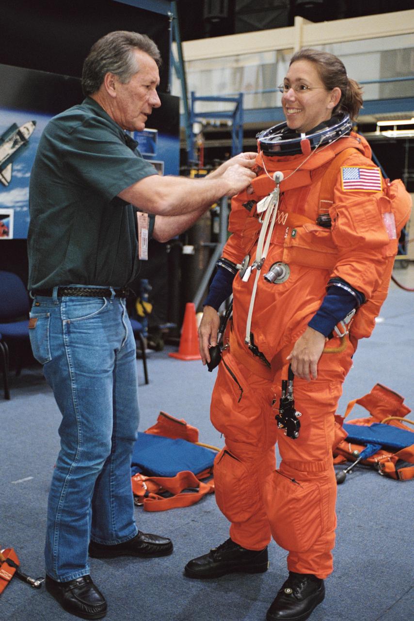 JSC2002-00789 (12 April 2002) --- Astronaut Sandra H. Magnus, STS-112 mission specialist, dons a training version of the full-pressure launch and entry suit, prior to the start of a photo and training session in the Space Vehicle Mockup Facility at the Johnson Space Center (JSC). United Space Alliance (USA) suit technician Jim Cheatham assisted Magnus. STS-112 will be the 15th shuttle mission to visit the International Space Station (ISS).