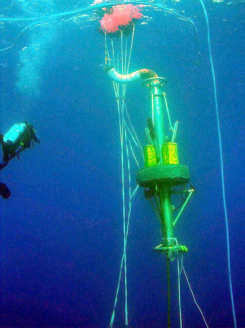 KENNEDY SPACE CENTER, FLA. -- A Diver Operator Plug (DOP) is being pulled down into the ocean by a newly designed one-man submarine known as DeepWorker 2000. The activity is part of an operation to attach the plug to a mockup of a solid rocket booster nozzle. DeepWorker 2000 is being tested on its ability to duplicate the sometimes hazardous job United Space Alliance (USA) divers perform to recover the expended boosters in the ocean after a launch. The boosters splash down in an impact area about 140 miles east of Jacksonville and after recovery are towed back to KSC for refurbishment by the specially rigged recovery ships. DeepWorker 2000 will be used in a demonstration during retrieval operations after the upcoming STS-101 launch. The submarine pilot will demonstrate capabilities to cut tangled parachute riser lines using a manipulator arm and attach the DOP to extract water and provide flotation for the booster. DeepWorker 2000 was built by Nuytco Research Ltd., North Vancouver, British Columbia. It is 8.25 feet long, 5.75 feet high, and weighs 3,800 pounds. USA is a prime contractor to NASA for the Space Shuttle program