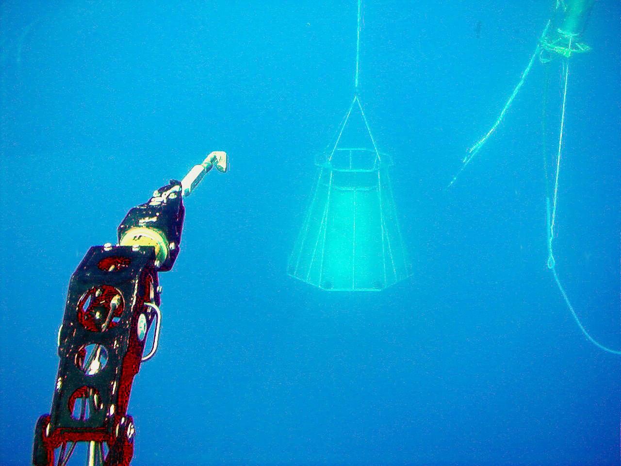 KENNEDY SPACE CENTER, FLA. -- At left, a manipulator arm on a one-man submarine demonstrates its ability to cut tangled parachute riser lines and place a Diver Operator Plug (top right) inside a mock solid rocket booster nozzle (center). Known as DeepWorker 2000, the sub is being tested on its ability to duplicate the sometimes hazardous job United Space Alliance (USA) divers perform to recover the expended boosters in the ocean after a launch. The boosters splash down in an impact area about 140 miles east of Jacksonville and after recovery are towed back to KSC for refurbishment by the specially rigged recovery ships. DeepWorker 2000 will be used in a demonstration during retrieval operations after the upcoming STS-101 launch. The submarine pilot will demonstrate capabilities to cut tangled parachute riser lines using a manipulator arm and attach the DOP to extract water and provide flotation for the booster. DeepWorker 2000 was built by Nuytco Research Ltd., North Vancouver, British Columbia. It is 8.25 feet long, 5.75 feet high, and weighs 3,800 pounds. USA is a prime contractor to NASA for the Space Shuttle program