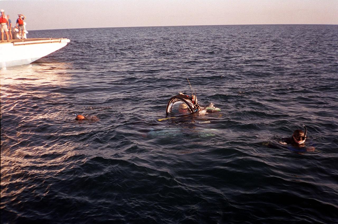 KENNEDY SPACE CENTER, FLA. -- The one-man submarine known as DeepWorker 2000 is tested in Atlantic waters near Cape Canaveral, Fla. Nearby are divers; inside the sub is the pilot, Anker Rasmussen. The sub is being tested on its ability to duplicate the sometimes hazardous job United Space Alliance (USA) divers perform to recover the expended boosters in the ocean after a launch. The boosters splash down in an impact area about 140 miles east of Jacksonville and after recovery are towed back to KSC for refurbishment by the specially rigged recovery ships. DeepWorker 2000 will be used in a demonstration during retrieval operations after the upcoming STS-101 launch. The submarine pilot will demonstrate capabilities to cut tangled parachute riser lines using a manipulator arm and attach a Diver Operator Plug to extract water and provide flotation for the booster. DeepWorker 2000 was built by Nuytco Research Ltd., North Vancouver, British Columbia. It is 8.25 feet long, 5.75 feet high, and weighs 3,800 pounds. USA is a prime contractor to NASA for the Space Shuttle program