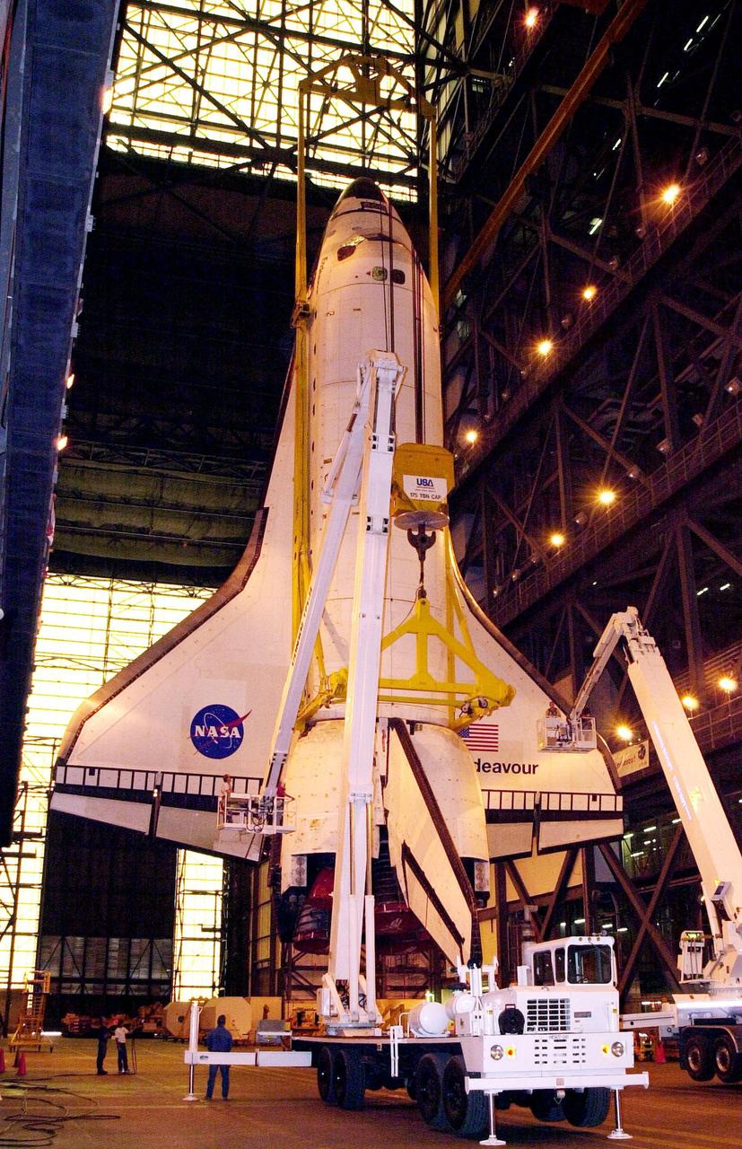KENNEDY SPACE CENTER, FLA. -- As the orbiter Endeavour hangs suspended from a crane inside the Vehicle Assembly Building, workers make adjustments on it before it is lifted and stacked with its external tank and solid rocket boosters. The stack is in high bay 1. Space Shuttle Endeavour is scheduled to be launched Nov. 30 on mission STS-97, the sixth construction flight to the International Space Station