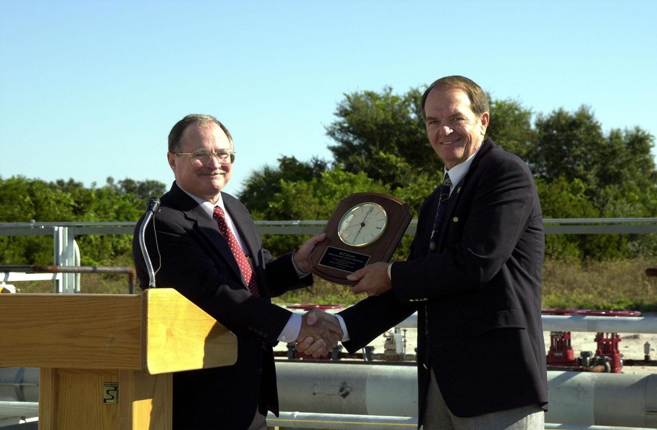 Jerry Jorgensen, pipeline project manager, Space Gateway Support (SGS) presents an award of appreciation to H.T. Everett, KSC Propellants manager, at the commissioning of a new high-pressure helium pipeline at Kennedy Space Center. The pipeline will service launch needs at the new Delta IV Complex 37 at Cape Canaveral Air Force Station. The nine-mile-long buried pipeline will also serve as a backup helium resource for Shuttle launches. Nearly one launch’s worth of helium will be available in the pipeline to support a Shuttle pad in an emergency. The line originates at the Helium Facility on KSC and terminates in a meter station at the perimeter of the Delta IV launch pad. Others at the ceremony were Center Director Roy Bridges;); Col. Samuel Dick, representative of the 45th Space Wing; Ramon Lugo, acting executive director, JPMO; David Herst, director, Delta IV Launch Sites; Pierre Dufour, president and CEO, Air Liquide America Corporation; and Michael Butchko, president, SGS