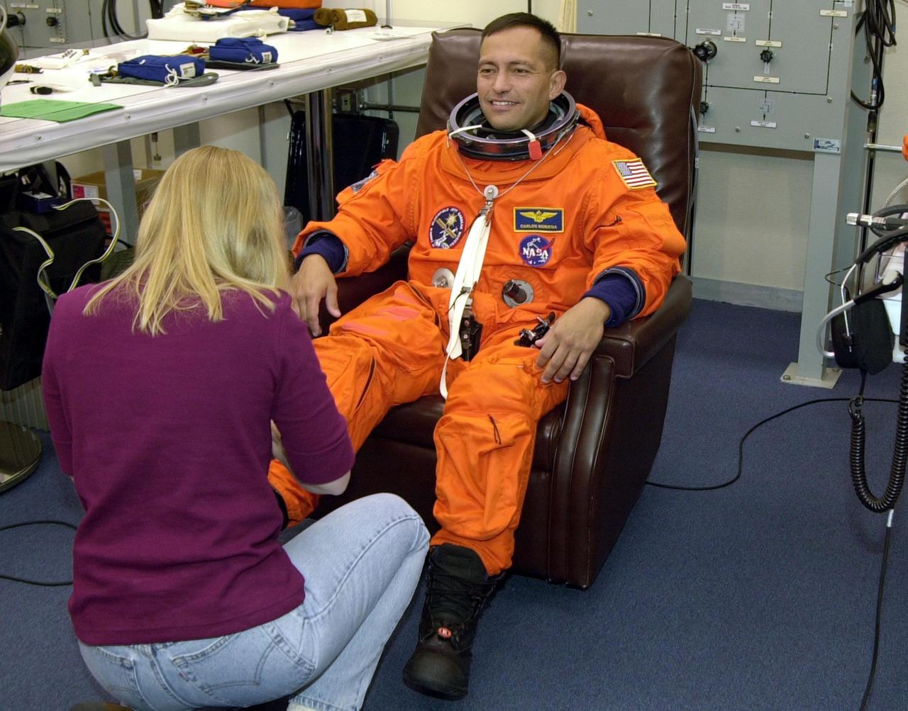 STS-97 Mission Specialist Carlos Noriega gets help with his boots from suit technician Shelly Grick-Agrella during pre-pack and fit check. Mission STS-97 is the sixth construction flight to the International Space Station. Its payload includes the P6 Integrated Truss Structure and a photovoltaic (PV) module, with giant solar arrays that will provide power to the Station. The mission includes two spacewalks to complete the solar array connections. STS-97 is scheduled to launch Nov. 30 at about 10:06 p.m. EST