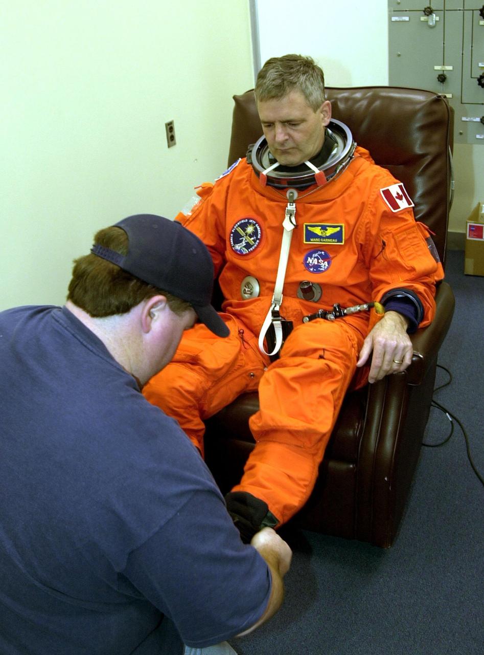 STS-97 Mission Specialist Marc Garneau gets help with his boots from suit technician Tommy McDonald during pre-pack and fit check. Garneau is with the Canadian Space Agency. Mission STS-97 is the sixth construction flight to the International Space Station. Its payload includes the P6 Integrated Truss Structure and a photovoltaic (PV) module, with giant solar arrays that will provide power to the Station. The mission includes two spacewalks to complete the solar array connections. STS-97 is scheduled to launch Nov. 30 at about 10:06 p.m. EST