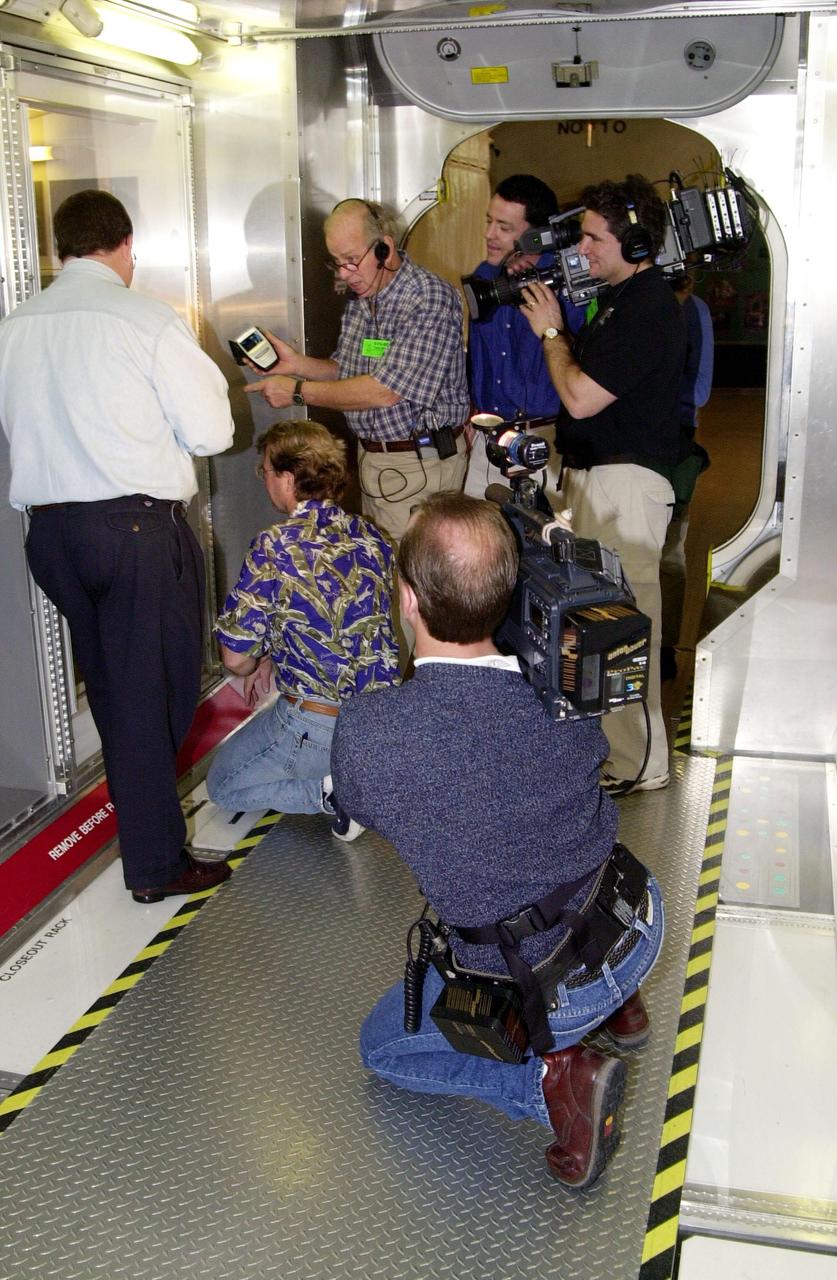 KENNEDY SPACE CENTER, FLA. -- A film crew gather around Steve Thomas (kneeling) as they shoot inside a mockup of the U.S. Lab, located in the International Space Station Center, a tour facility. Thomas and Norm Abram, host and master carpenter, respectively, of television’s  "This Old House," are at KSC to film an episode of the series