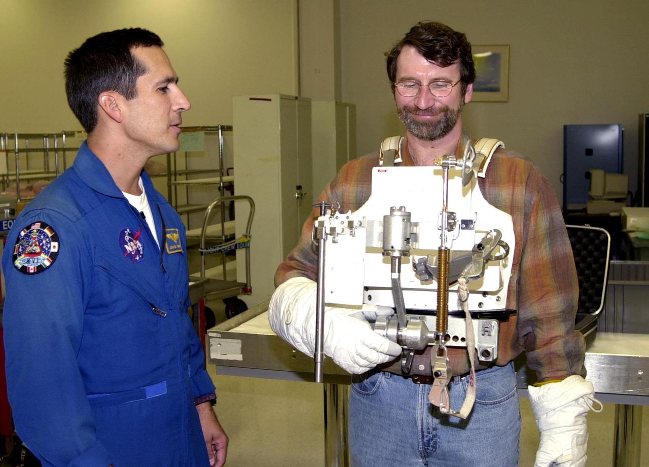 KENNEDY SPACE CENTER, FLA. -- While astronaut John Herrington (left) looks on, Norm Abram tries on a tool carrier used in space. Abram is master carpenter of television’s "This Old House" and "The New Yankee Workshop." He is at KSC to film an episode of "This Old House.