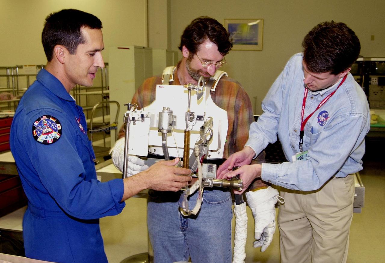 KENNEDY SPACE CENTER, FLA. -- After trying on a tool carrier, master carpenter of television’s "This Old House" and "The New Yankee Workshop" Norm Abram (center) receives assistance from astronaut John Herrington (left) and Phil West (right), with Johnson Space Center. Abram is at KSC to film an episode of "This Old House.