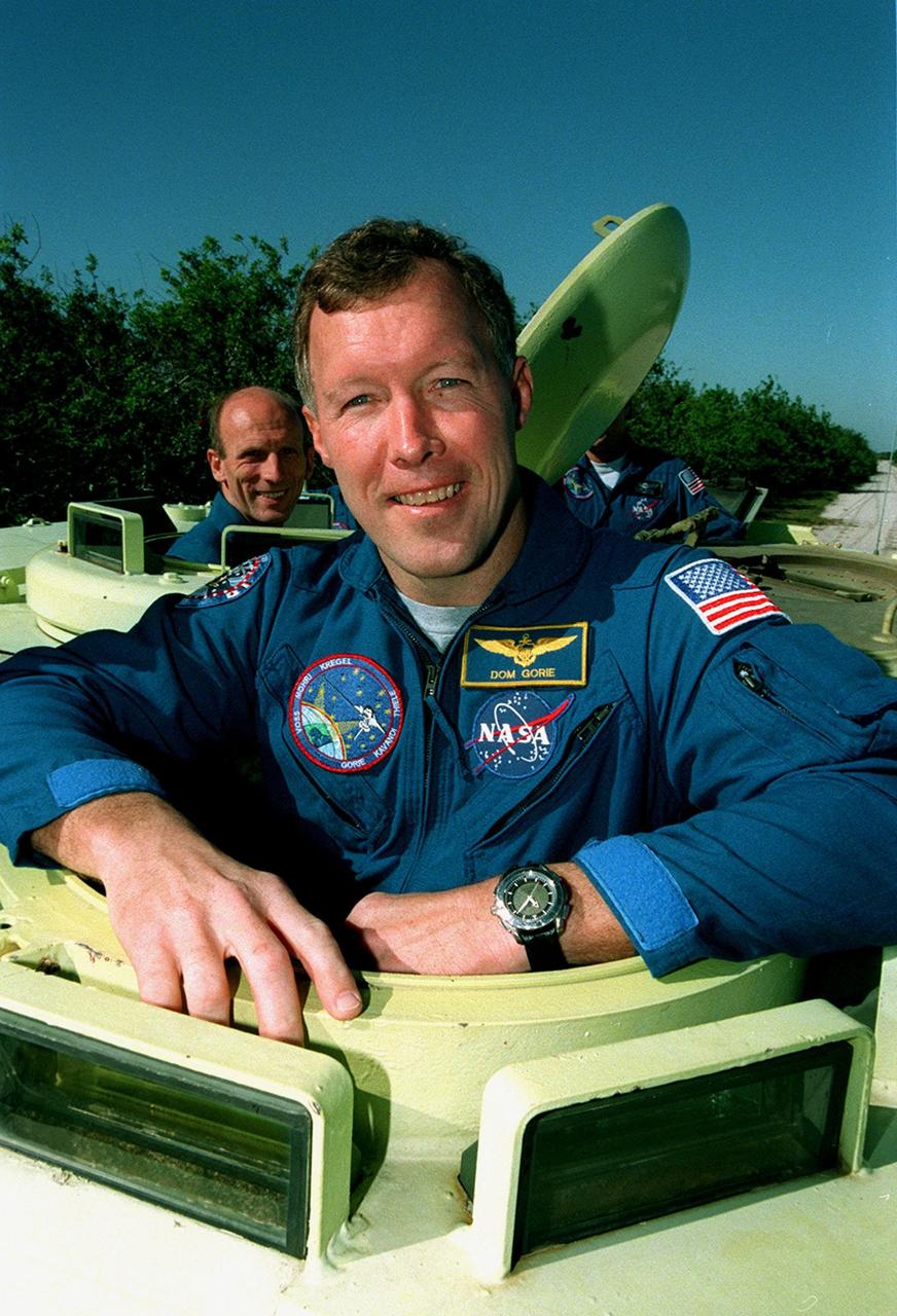 During Terminal Countdown Demonstration Test (TCDT) activities, STS-99 Pilot Dominic Gorie , is ready to practice driving an armored personnel carrier that is part of emergency egress training and could be used by the crew in the event of an emergency at the pad during which the crew must make a quick exit from the area. Behind him (left) is Mission Specialist Gerhard Thiele, who is with the European Space Agency. TCDT provides the crew with simulated countdown exercises, emergency egress training, and opportunities to inspect the mission payloads in the orbiter's payload bay. STS-99 is the Shuttle Radar Topography Mission, which will chart a new course, using two antennae and a 200-foot-long section of space station-derived mast protruding from the payload bay to produce unrivaled 3-D images of the Earth's surface. The result of the Shuttle Radar Topography Mission could be close to 1 trillion measurements of the Earth's topography. Besides contributing to the production of better maps, these measurements could lead to improved water drainage modeling, more realistic flight simulators, better locations for cell phone towers, and enhanced navigation safety. Launch of Endeavour on the 11-day mission is scheduled for Jan. 31 at 12:47 p.m. EST