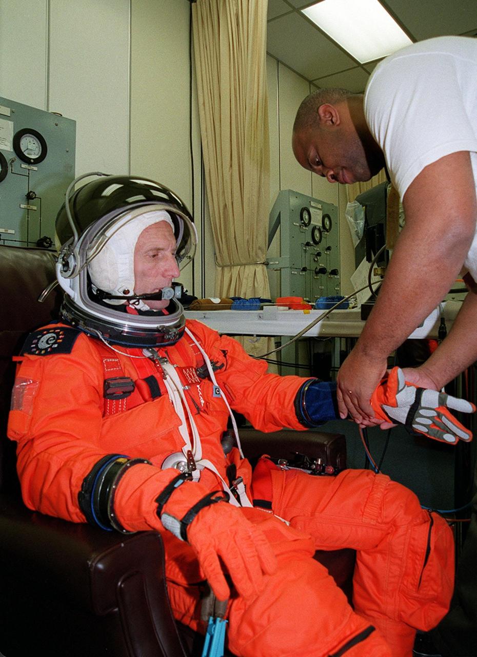 STS-99 Mission Specialist Gerhard Thiele, with the European Space Agency, gets help from a suit technician in the Operations and Checkout Building, as part of flight crew equipment fit check, prior to his trip to Launch Pad 39A. The crew is taking part in Terminal Countdown Demonstration Test (TCDT) activities that provide the crew with simulated countdown exercises, emergency egress training, and opportunities to inspect the mission payloads in the orbiter's payload bay. STS-99 is the Shuttle Radar Topography Mission, which will chart a new course, using two antennae and a 200-foot-long section of space station-derived mast protruding from the payload bay to produce unrivaled 3-D images of the Earth's surface. The result of the Shuttle Radar Topography Mission could be close to 1 trillion measurements of the Earth's topography. Besides contributing to the production of better maps, these measurements could lead to improved water drainage modeling, more realistic flight simulators, better locations for cell phone towers, and enhanced navigation safety. Launch of Endeavour on the 11-day mission is scheduled for Jan. 31 at 12:47 p.m. EST