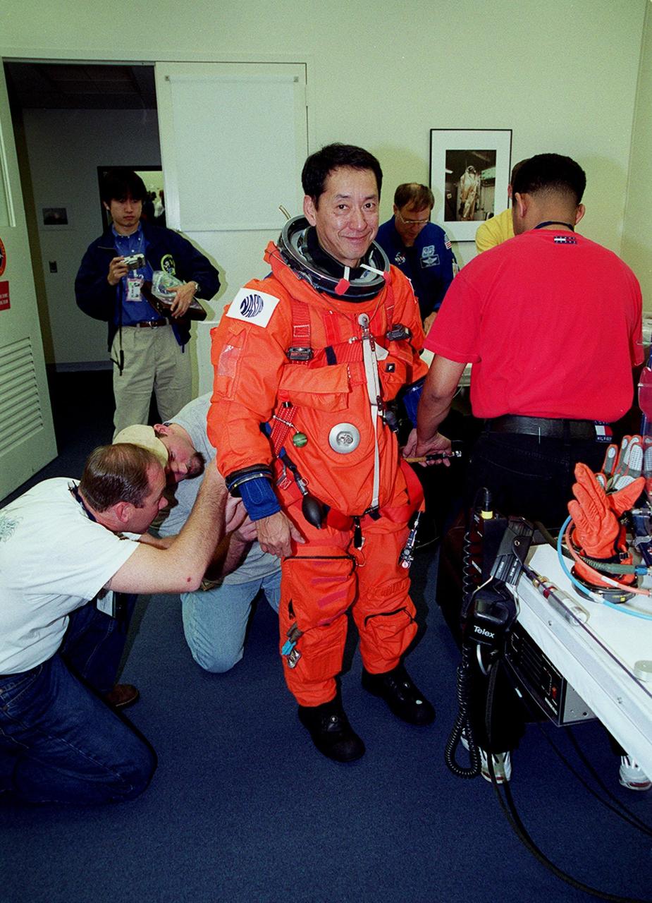 In the Operations and Checkout Building, STS-99 Mission Specialist Mamoru Mohri, who is with the National Space Development Agency (NASDA) of Japan, gets help from suit technicians during flight crew equipment fit check prior to his trip to Launch Pad 39A. The crew is taking part in Terminal Countdown Demonstration Test (TCDT) activities that provide the crew with simulated countdown exercises, emergency egress training, and opportunities to inspect the mission payloads in the orbiter's payload bay. STS-99 is the Shuttle Radar Topography Mission, which will chart a new course, using two antennae and a 200-foot-long section of space station-derived mast protruding from the payload bay to produce unrivaled 3-D images of the Earth's surface. The result of the Shuttle Radar Topography Mission could be close to 1 trillion measurements of the Earth's topography. Besides contributing to the production of better maps, these measurements could lead to improved water drainage modeling, more realistic flight simulators, better locations for cell phone towers, and enhanced navigation safety. Launch of Endeavour on the 11-day mission is scheduled for Jan. 31 at 12:47 p.m. EST