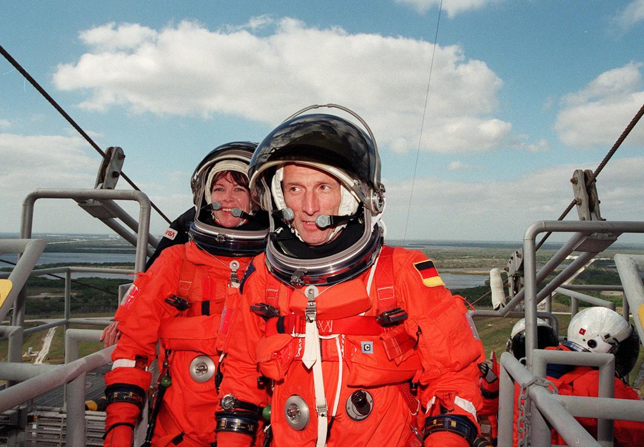At Launch Pad 39A, STS-99 Mission Specialists Gerhard Thiele (Ph.D.), of the European Space Agency (in front), and Janet Kavandi (Ph.D.) prepare to practice emergency egress procedures with a slidewire basket. Seven slidewires, with flatbottom baskets suspended from each wire, extend from the Fixed Service Structure at the orbiter access arm level. These baskets could provide an escape route for the astronauts until the final 30 seconds of the countdown in case of an emergency. The crew is taking part in Terminal Countdown Demonstration Test (TCDT) activities that provide the crew with simulated countdown exercises, emergency egress training, and opportunities to inspect the mission payloads in the orbiter's payload bay. STS-99 is the Shuttle Radar Topography Mission, which will chart a new course, using two antennae and a 200-foot-long section of space station-derived mast protruding from the payload bay to produce unrivaled 3-D images of the Earth's surface. The result of the Shuttle Radar Topography Mission could be close to 1 trillion measurements of the Earth's topography. Besides contributing to the production of better maps, these measurements could lead to improved water drainage modeling, more realistic flight simulators, better locations for cell phone towers, and enhanced navigation safety. Launch of Endeavour on the 11-day mission is scheduled for Jan. 31 at 12:47 p.m. EST