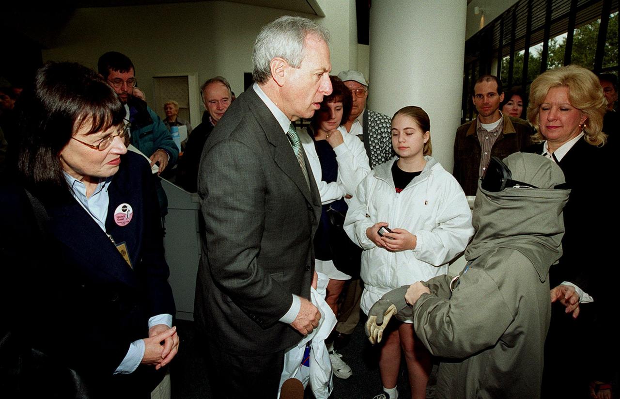 NASA Administrator Dan Goldin (center) greets 10-year-old Jonathan Pierce (right), who is garbed in a protective cooling suit designed by NASA. In the background, between them, are Jonathan's mother, Penny; his grandfather, John Janocka; and his sister, Jaimie.. At left is Mrs. Goldin. Jonathan suffers from erythropoietic protoporphyria, a rare condition that makes his body unable to withstand ultraviolet rays. The suit allows him to be outside during the day, which would otherwise be impossible. Jonathan's trip was funded by the Make-A-Wish Foundation and included a visit to Disney World. He and his family were among a dozen VIPs at KSC to view the launch of STS-99