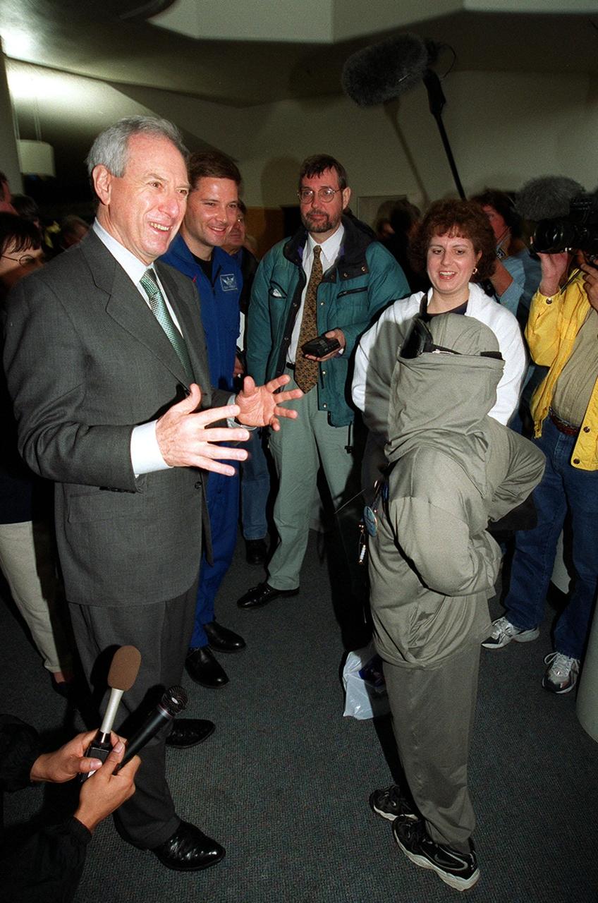 NASA Administrator Dan Goldin (left) shares a light moment during his meeting with 10-year-old Jonathan Pierce (right), who is garbed in a protective cooling suit designed by NASA. Behind Goldin is astronaut Doug Wheelock; behind Jonathan is his mother, Penny. Jonathan suffers from erythropoietic protoporphyria, a rare condition that makes his body unable to withstand ultraviolet rays. The suit allows him to be outside during the day, which would otherwise be impossible. Jonathan's trip was funded by the Make-A-Wish Foundation and included a visit to Disney World. He and his family were among a dozen VIPs at KSC to view the launch of STS-99