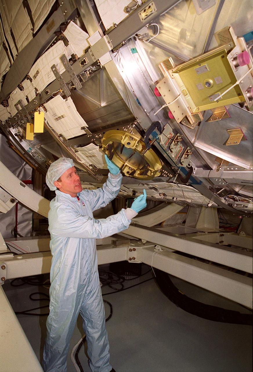 In the Space Station Processing Facility, STS-98 Mission Specialist Thomas D. Jones (Ph.D.) examines a power data grapple fixture outside the U.S. Lab Destiny. Jones is taking part in a Multi-Equipment Interface Test (MEIT), along with other crew members Commander Kenneth D. Cockrell and Pilot Mark Polansky. The remaining members of the crew (not present for the MEIT) are Mission Specialists Robert L. Curbeam Jr. and Marsha S. Ivins. During the STS-98 mission, the crew will install the Lab on the International Space Station during a series of three space walks. The grapple fixture will be the base of operations for the robotic arm on later flights The mission will provide the station with science research facilities and expand its power, life support and control capabilities. The U.S. Laboratory Module continues a long tradition of microgravity materials research, first conducted by Skylab and later Shuttle and Spacelab missions. Destiny is expected to be a major feature in future research, providing facilities for biotechnology, fluid physics, combustion, and life sciences research. The Lab is planned for launch aboard Space Shuttle Atlantis on the sixth ISS flight, currently targeted no earlier than Aug. 19, 2000