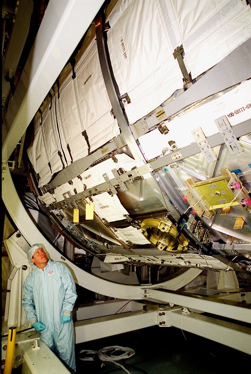 KENNEDY SPACE CENTER, FLA. -- In the Space Station Processing Facility, STS-98 Mission Specialist Thomas D. Jones (Ph.D.) looks up at the U.S. Lab Destiny with its debris shield blanket made of a material similar to that used in bullet-proof vests on Earth. Along with Commander Kenneth D. Cockrell and Pilot Mark Polansky, Jones is taking part in a Multi-Equipment Interface Test (MEIT) on this significant element of the International Space Station. During the STS-98 mission, the crew will install the Lab on the Station during a series of three spacewalks. The mission will provide the Station with science research facilities and expand its power, life support and control capabilities. The U.S. Laboratory Module continues a long tradition of microgravity materials research, first conducted by Skylab and later Shuttle and Spacelab missions. Destiny is expected to be a major feature in future research, providing facilities for biotechnology, fluid physics, combustion and life sciences reseach. The Lab is planned for launch aboard Space Shuttle Atlantis on the sixth ISS flight, currently targeted no earlier than August 19, 2000.