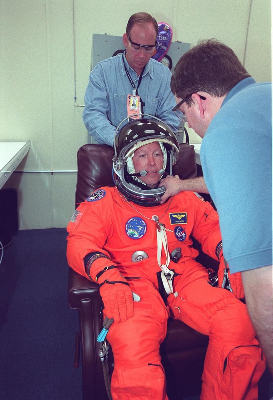 In the Operations and Checkout Building, STS-99 Pilot Dominic Gorie has his helmet checked by Santos Medina, with United Space Alliance, during final launch preparations. Known as the Shuttle Radar Topography Mission (SRTM), STS-99 is scheduled for liftoff at 12:30 p.m. EST from Launch Pad 39A. The SRTM will chart a new course to produce unrivaled 3-D images of the Earth's surface. The result of the Shuttle Radar Topography Mission could be close to 1 trillion measurements of the Earth's topography. The mission is expected to last 11days, with Endeavour landing at KSC Tuesday, Feb. 22, at 4:36 p.m. EST. This is the 97th Shuttle flight and 14th for Shuttle Endeavour