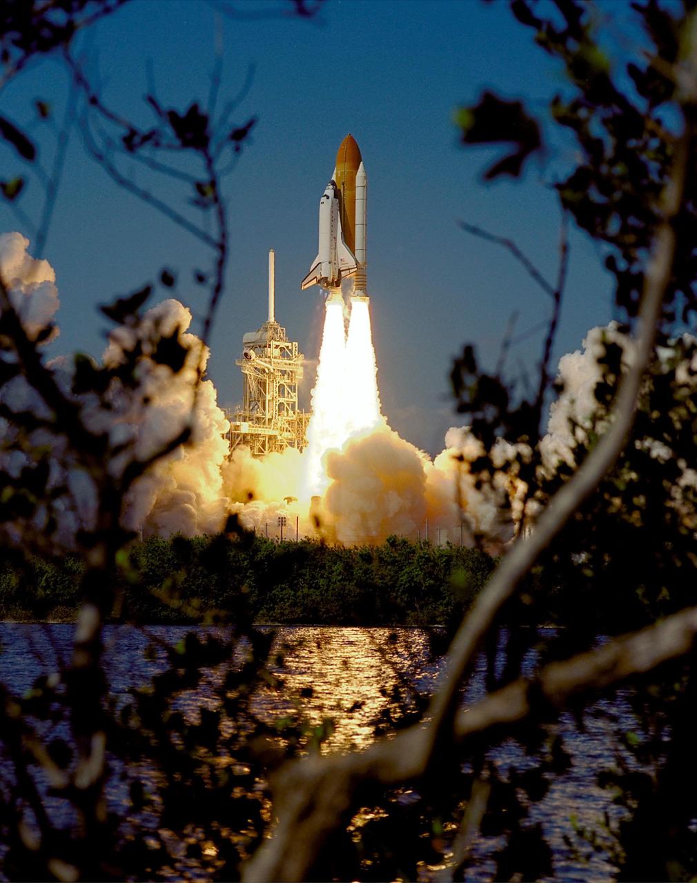 KENNEDY SPACE CENTER, Fla. -- Through the shrubs surrounding the water near Launch Pad 39A can be seen Space Shuttle Endeavour roaring into the clear blue Florida sky on mission STS-99. aunch of Endeavour occurred at 12:43:40 p.m. EST. Known as the Shuttle Radar Topography Mission (SRTM), STS-99 will chart a new course to produce unrivaled 3-D images of the Earth's surface. The result of the SRTM could be close to 1 trillion measurements of the Earth's topography. The mission is expected to last 11days, with Endeavour landing at KSC Tuesday, Feb. 22, at 4:36 p.m. EST. This is the 97th Shuttle flight and 14th for Shuttle Endeavour