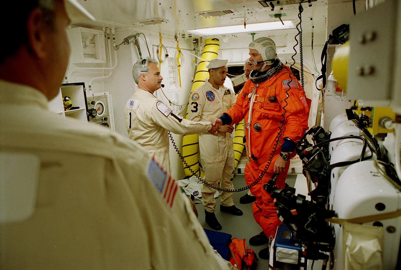 Before entering the orbiter Endeavour, STS-99 Commander Kevin Kregel shakes hands with Chris Meinert, closeout chief of the White Room closeout crew. In the background is Carlos Gillis, suit technician. The White Room is an environmental chamber at the end of the orbiter access arm, on the fixed service structure, that provides entry to the orbiter crew compartment. STS-99, known as the Shuttle Radar Topography Mission (SRTM), will chart a new course to produce unrivaled 3-D images of the Earth's surface. The result of the Shuttle Radar Topography Mission could be close to 1 trillion measurements of the Earth's topography. Scheduled for liftoff at 12:30 p.m. EST, the mission is expected to last 11days, with Endeavour landing at KSC Tuesday, Feb. 22, at 4:36 p.m. EST. This is the 97th Shuttle flight and 14th for Shuttle Endeav