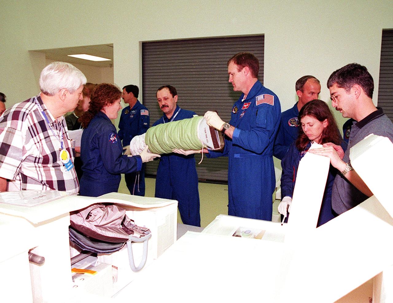 KENNEDY SPACE CENTER, FLA. -- At SPACEHAB, in Cape Canaveral, Fla., STS-101 Mission Specialists Susan Helms and Yuri Usachev, with Commander James Halsell, handle an air duct to be installed during their mission to the International Space Station. The air duct is for the Russian module Zarya to improve ventilation. At right are Mission Specialists Jeffrey Williams and Mary Ellen Weber. In the background at left is Pilot Scott Horowitz. Not shown is Mission Specialist James Voss. The crew is taking part in Crew Equipment Interface Test (CEIT) activities to learn about some of the equipment they will be working with on their mission to the Space Station. The STS-101 crew will be responsible for preparing the Space Station for the arrival of the Zvezda Service Module, expected to be launched by Russia in July 2000. Also, the crew will conduct one space walk to perform maintenance on the Space Station and deliver logistics and supplies. This will be the third assembly flight for the Space Station. STS-101 is scheduled to launch no earlier than April 13 from Launch Pad 39A