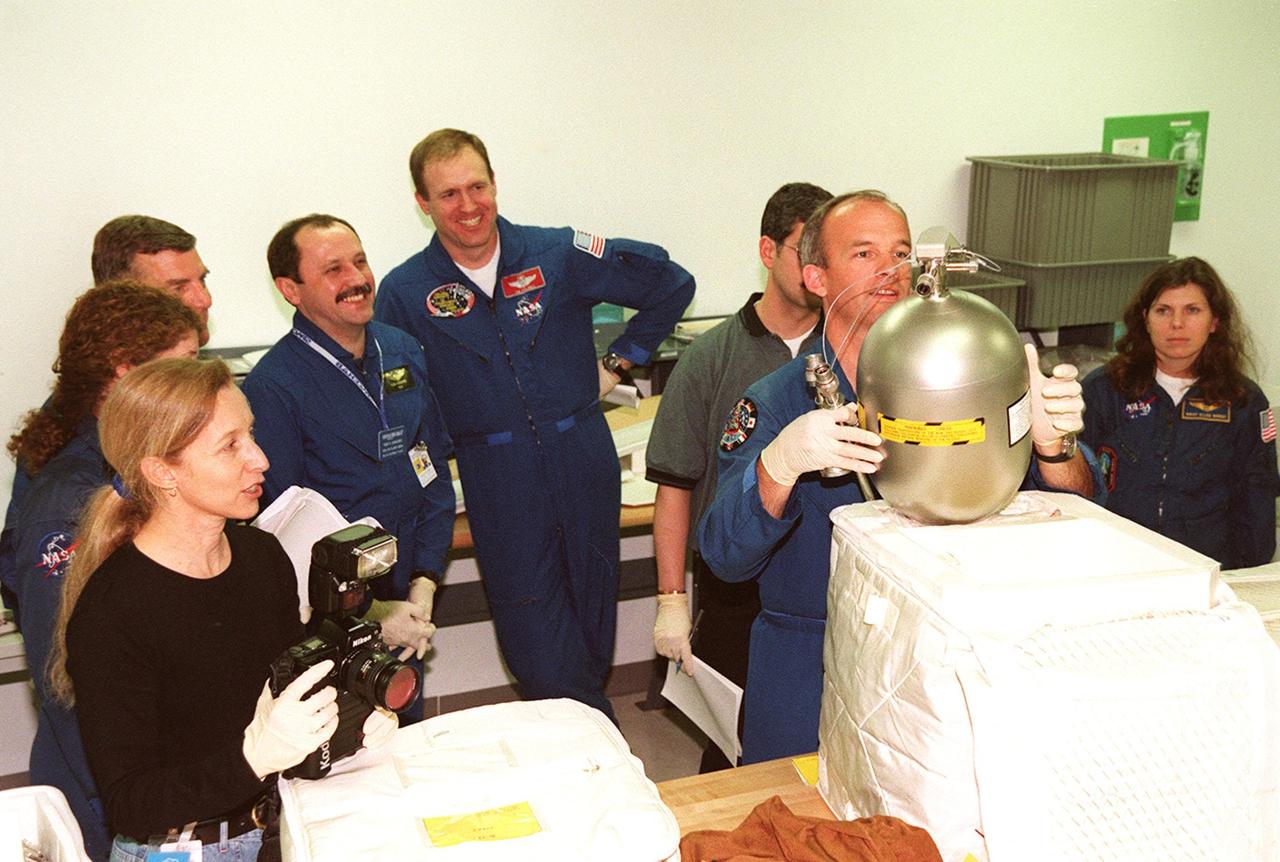 KENNEDY SPACE CENTER, FLA. -- Members of the STS-101 crew share a light moment during Crew Equipment Interface Test (CEIT) activities at SPACEHAB, in Cape Canaveral, Fla. Documenting the occasion is astronaut Marsha Ivins (far left, with camera). Standing behind her (left to right) are Mission Specialists Susan Helms, James Voss and Yuri Usachev; Commander James Halsell; and Mission Specialists Jeffrey Williams (holding tank) and Mary Ellen Weber. During a CEIT, a Shuttle crew becomes familiar with some of the equipment they will be working with on their mission. The STS-101 crew will be responsible for preparing the Space Station for the arrival of the Zvezda Service Module, expected to be launched by Russia in July 2000. Also, the crew will conduct one space walk to perform maintenance on the Space Station and deliver logistics and supplies. This will be the third assembly flight for the Space Station. STS-101 is scheduled to launch no earlier than April 13 from Launch Pad 39A