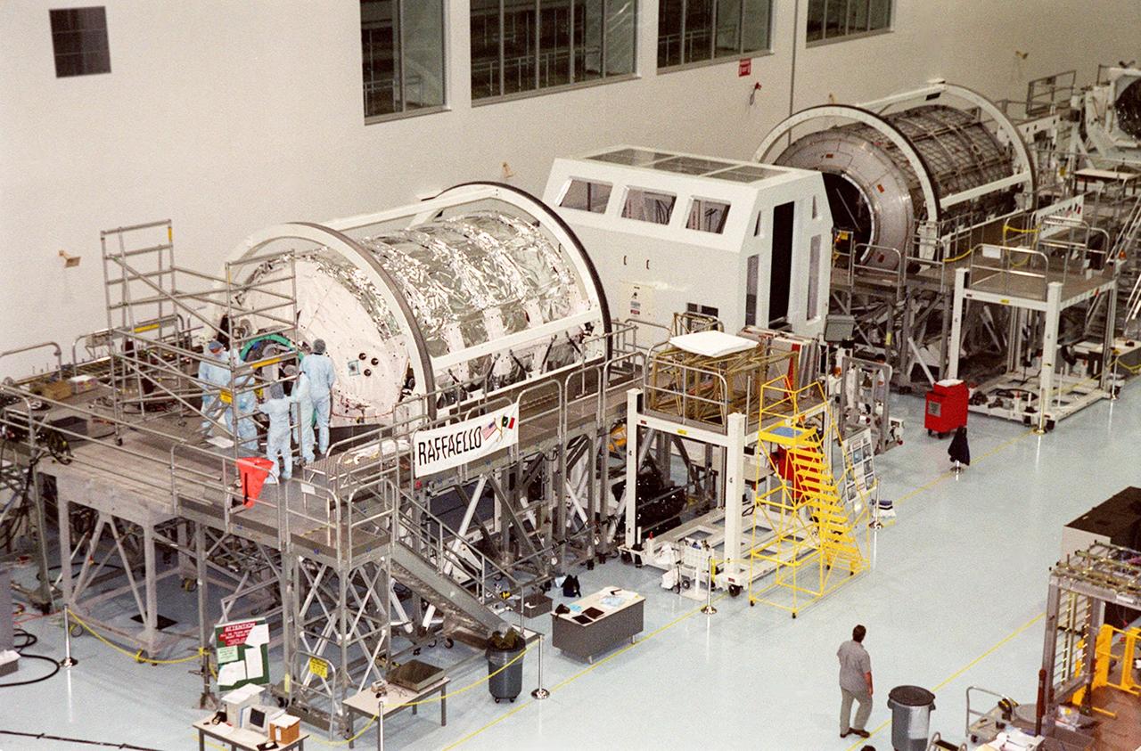 KENNEDY SPACE CENTER, FLA. -- Workers in the Space Station Processing Facility stand outside the Multi-Purpose Logistics Module (MPLM) Raffaello (left). At right is the MPLM Leonardo. They are reusable logistics carriers to resupply the International Space Station, and return cargo, that requires a pressurized environment. The MPLMs are slated as payloads on missions STS-102 and STS-100, respectively. Dates have not yet been determined for the two missions