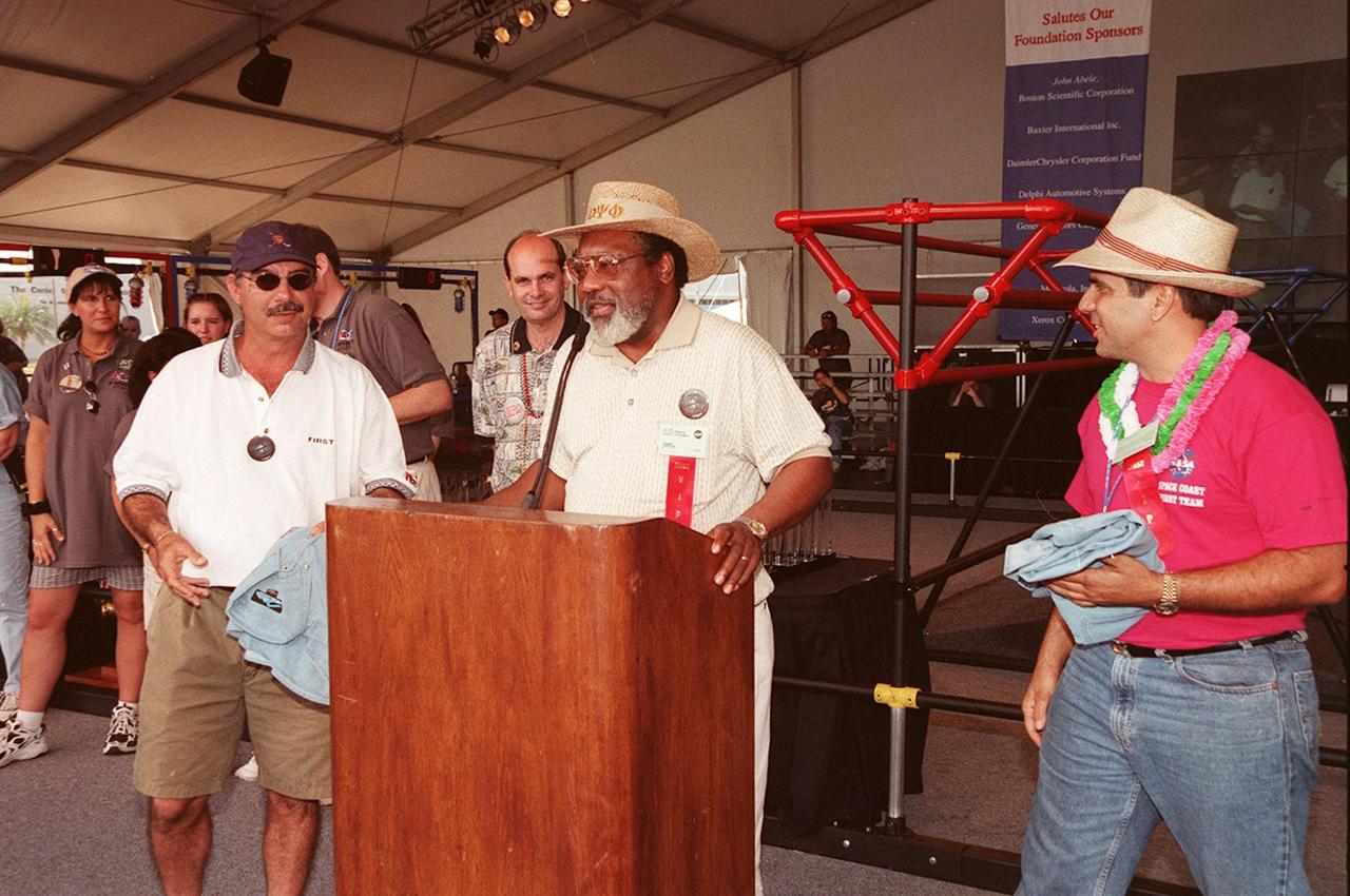 At the conclusion of the FIRST (For Inspiration and Recognition of Science and Technology) Southeast Regional competition held at the KSC Visitor Complex, the Center's Deputy Director for Business Operations Jim Jennings presents shirts to Dave Alonso (left) and Eduardo Lopez del Castillo (right). Alonso, who is chief of the Program Control Contract Office, helped make possible the KSC sponsorship of the event. Castillo helped introduce the FIRST organization to KSC several years ago. Teams of high school students from all over the country tested the limits of their imagination using robots they designed, with the support of business and engineering professionals and corporate sponsors, to compete in a technological battle against other schools' robots. Of the 30 high school teams competing at the Southeast Regional event, 16 were Florida teams co-sponsored by NASA and KSC contractors. Local high schools participating are Astronaut, Bayside, Cocoa Beach, Eau Gallie, Melbourne, Melbourne Central Catholic, Palm Bay, Rockledge, Satellite, and Titusville
