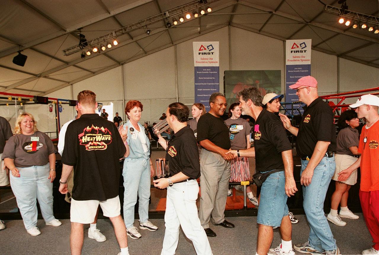 Adult members of the team known as Heatwave, from St. Petersburg, Fla., get &quot;high fives&quot; from Nap Carroll (center), chief financial officer, Kennedy Space Center, and other officials of the FIRST (For Inspiration and Recognition of Science and Technology) Southeast Regional competition held at the KSC Visitor Complex. Heatwave came in second for the final competition, plus received awards for Number One Seed, Best Offensive round, and the DaimlerChrysler Team Spirit. Teams of high school students from all over the country tested the limits of their imagination using robots they designed, with the support of business and engineering professionals and corporate sponsors, to compete in a technological battle against other schools' robots. Of the 30 high school teams competing at the Southeast Regional event, 16 were Florida teams co-sponsored by NASA and KSC contractors. Local high schools participating are Astronaut, Bayside, Cocoa Beach, Eau Gallie, Melbourne, Melbourne Central Catholic, Palm Bay, Rockledge, Satellite, and Titusvill