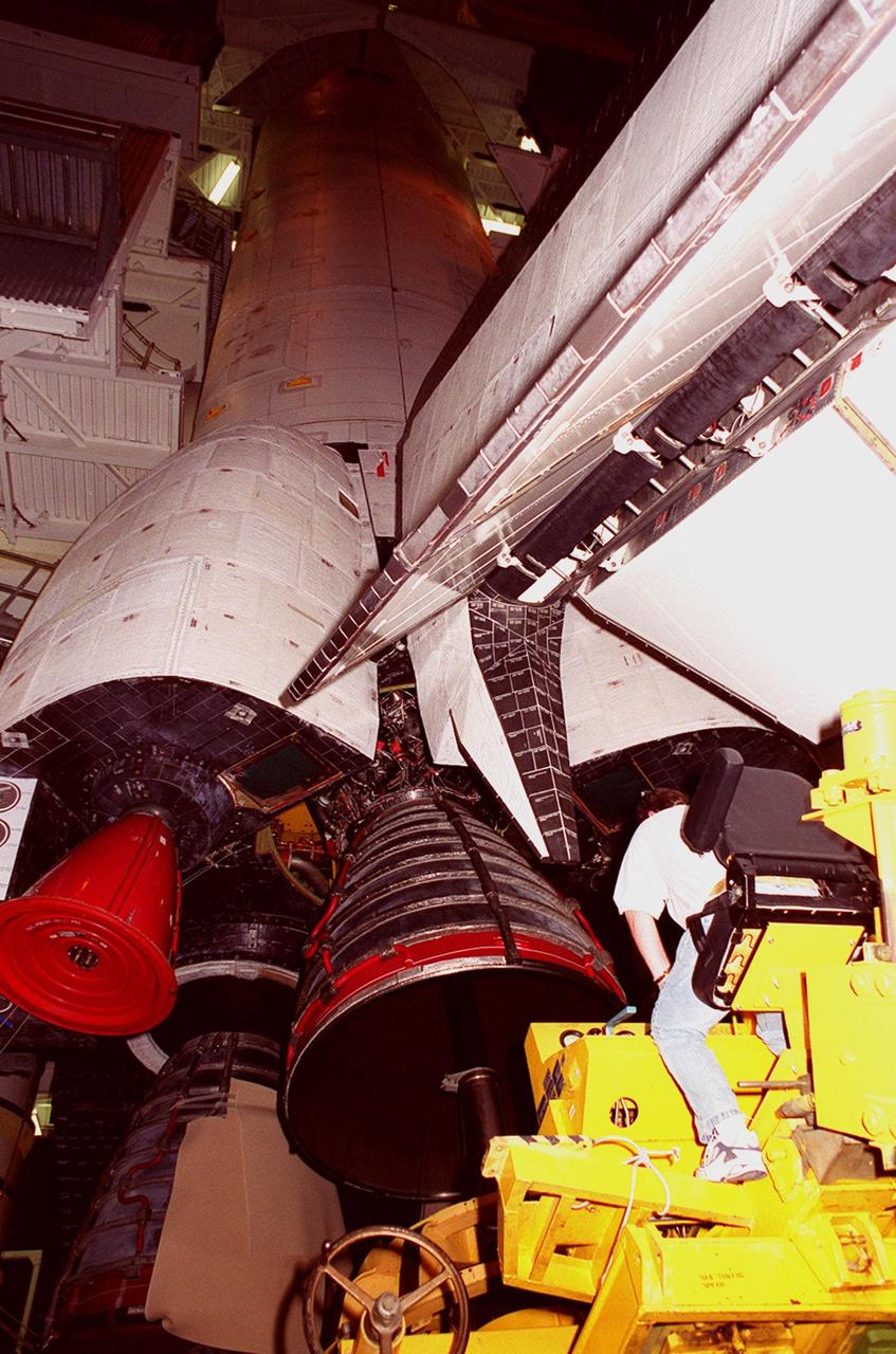 KENNEDY SPACE CENTER, FLA. -- Underneath the 26.3-foot vertical tail structure of Space Shuttle Atlantis, a worker in the Vehicle Assembly Building maneuvers equipment under Main Engine No. 1 in order to remove it. An inventory review concerning defective main engine fuel pump tip seals indicated that defective seals may be present on the fuel pump for the engine. The decision was made to replace the suspect engine with one originally slated for Discovery. The main engine nozzles, visible in the photo, are 7.8 feet across and 9.4 feet high. Space Shuttle Atlantis is scheduled to launch no earlier than April 17, 2000, on mission STS-101 to resupply the International Space Station for the arrival of the next pressurized module, the Russian-built Zvezda