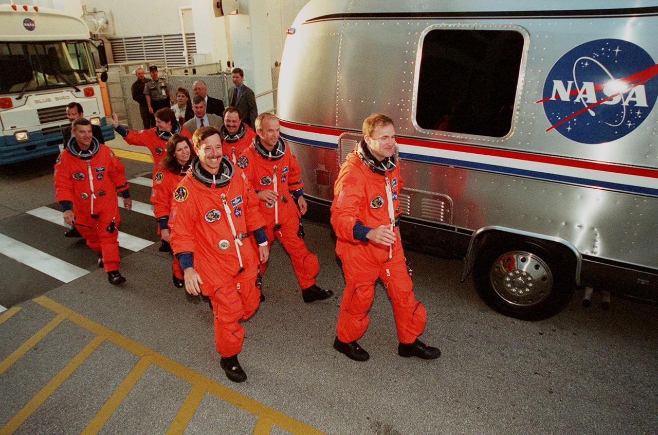 The STS-101 crew walk from the Operations and Checkout Building to the Astrovan, which will take them to Space Shuttle Atlantis on Launch Pad 39A for a simulated countdown exercise. Leading the way are (left) Pilot Scott J. "Doc" Horowitz and (right) Commander James D. Halsell Jr. In the second row are Mission Specialists (left) Mary Ellen Weber and (right) Jeffrey N. Williams. In the third row are Mission Specialists (left) James Voss, (waving) Susan J. Helms, and (right) Yury Usachev of Russia. The dress rehearsal for launch is part of Terminal Countdown Demonstration Test (TCDT) activities that include emergency egress training and familiarization with the payload. During their mission to the International Space Station, the STS-101 crew will be delivering logistics and supplies, plus preparing the Station for the arrival of the Zvezda Service Module, expected to be launched by Russia in July 2000. Also, the crew will conduct one space walk to perform maintenance on the Space Station. This will be the third assembly flight for the Space Station. STS-101 is scheduled to launch April 24 at 4:15 p.m. from Launch Pad 39A