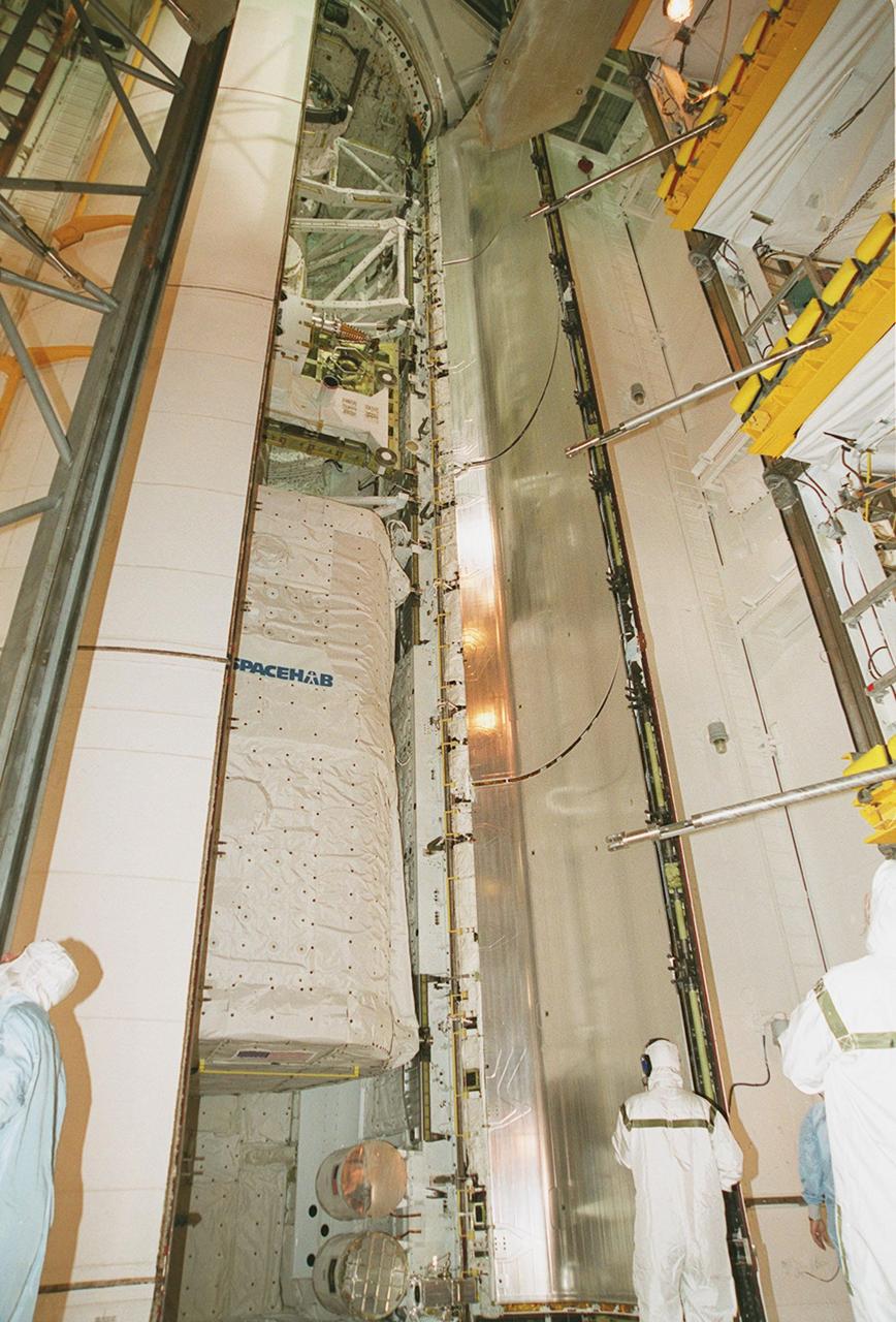 KENNEDY SPACE CENTER, FLA. -- Works at Launch Pad 39A begin closing the payload bay doors on Space Shuttle Atlantis. The payload includes the SPACEHAB Double Module (center) and two GetAway Special (GAS) canisters containing student experiments, known as MARS and SEM-06. The primary mission of STS-101 is to deliver logistics and supplies to the International Space Station, plus prepare the Station for the arrival of the Zvezda Service Module, expected to be launched by Russia in July 2000. The crew will conduct one space walk to perform maintenance on the Space Station. This will be the third assembly flight for the Space Station. STS-101 is scheduled to launch April 24 at 4:15 p.m. from Launch Pad 39A