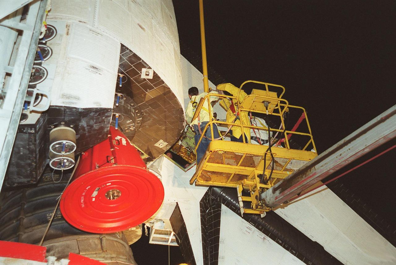 KENNEDY SPACE CENTER, FLA. -- At Launch Pad 39A, workers help guide the replacement Power Drive Unit (PDU) for Space Shuttle Atlantis into place. The PDU controls the rudder/speed brake on the orbiter. Atlantis is scheduled to lift off April 24 at 4:15 p.m. EDT on mission STS-101, the third flight to the International Space Station. The primary mission is to carry logistics and supplies to the Space Station, plus the crew will be preparing the Station for the arrival of the Zvezda Service Module, expected to be launched by Russia in July 2000