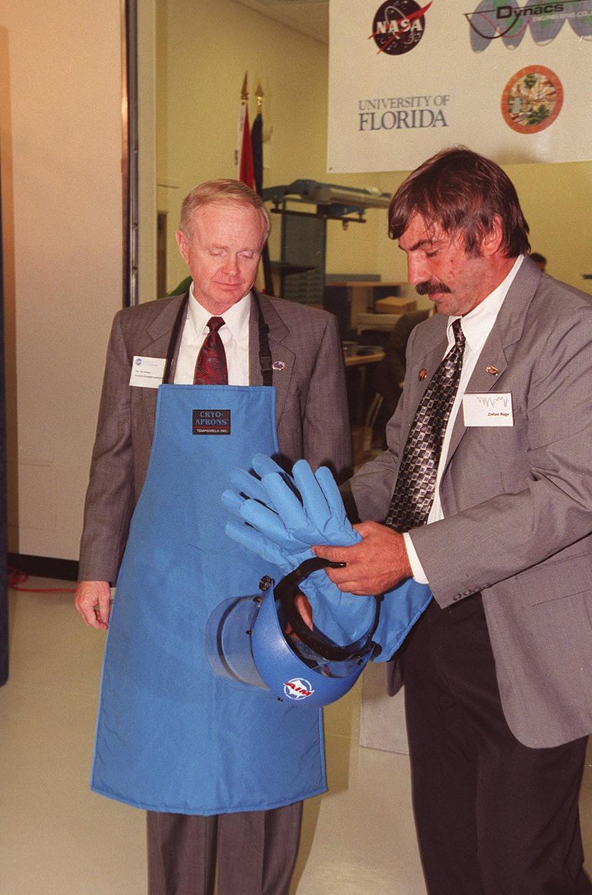 Center Director Roy Bridges (left) dons protective apron, gloves and face shield before the "ribbon-breaking" to open the new Cryogenic Testbed Facility. Part of the normal ceremonial ribbon was replaced with plastic tubing and frozen in liquid nitrogen for the event. Bridges hit the tubing with a small hammer to break it. The Cryogenics Testbed was built to provide cryogenics engineering development and testing services to meet the needs of industry. It will also support commercial, government and academic customers for technology development initiatives on the field of cryogenics. The facility is jointly managed by NASA and Dynacs Engineering Co. , NASA/SC's Engineering Development contractor