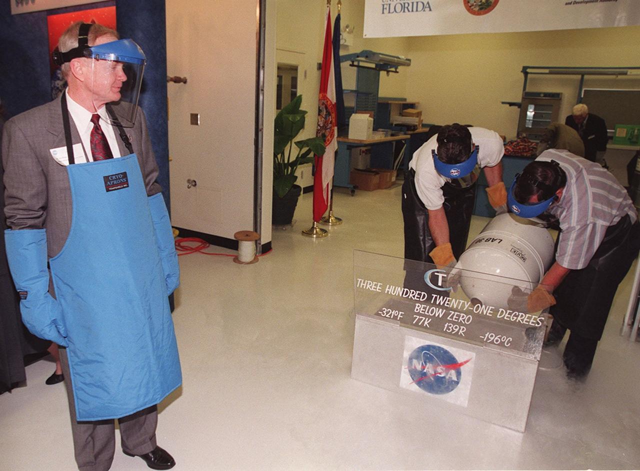 Center Director Roy Bridges (left), wearing protective apron, gloves and face shield, watches as liquid nitrogen is poured into a container to freeze the plastic tubing for a special "ribbon-breaking" to open the new Cryogenic Testbed Facility. Bridges hit the section of tubing with a small hammer to break it. The Cryogenics Testbed was built to provide cryogenics engineering development and testing services to meet the needs of industry. It will also support commercial, government and academic customers for technology development initiatives on the field of cryogenics. The facility is jointly managed by NASA and Dynacs Engineering Co. , NASA/SC's Engineering Development contractor