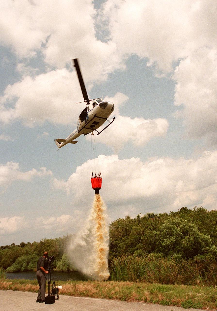 KENNEDY SPACE CENTER, FLA. -- A NASA helicopter releases the contents of the high-impact-resistant flexible plastic bucket it holds. The 324-gallon container will be used for fire protection on property and buildings at Kennedy Space Center. Known as the "Bambi" bucket, it will also support the Fish and Wildlife Service for controlled burns plus any wild fires in the area.