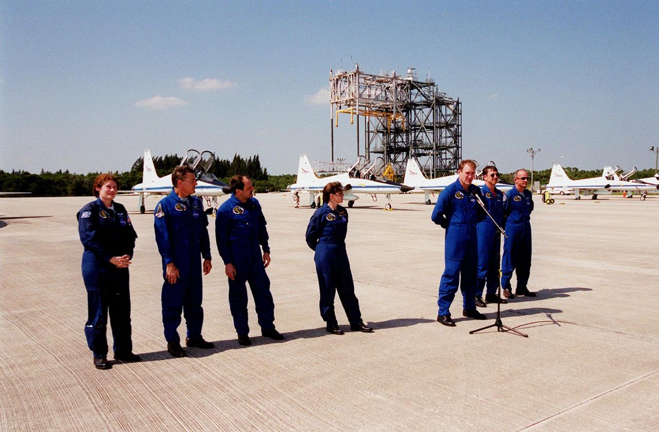 After arriving at the Shuttle Landing Facility for launch preparations, the STS-101 crew pauses to greet the media. Standing (left to right) are Mission Specialists Susan Helms, James Voss, Yury Usachev of Russia and Mary Ellen Weber; Commander James Halsell; Pilot Scott "Doc" Horowitz; and Mission Specialist Jeffrey Williams. The mission will take the crew to the International Space Station, delivering logistics and supplies, plus preparing the Station for the arrival of the Zvezda Service Module, expected to be launched by Russia in July 2000. Also, the crew will conduct one space walk to perform maintenance on the Space Station. This will be the third assembly flight for the Space Station. Launch is targeted for April 24 at about 4:15 p.m. EDT from Launch Pad 39A