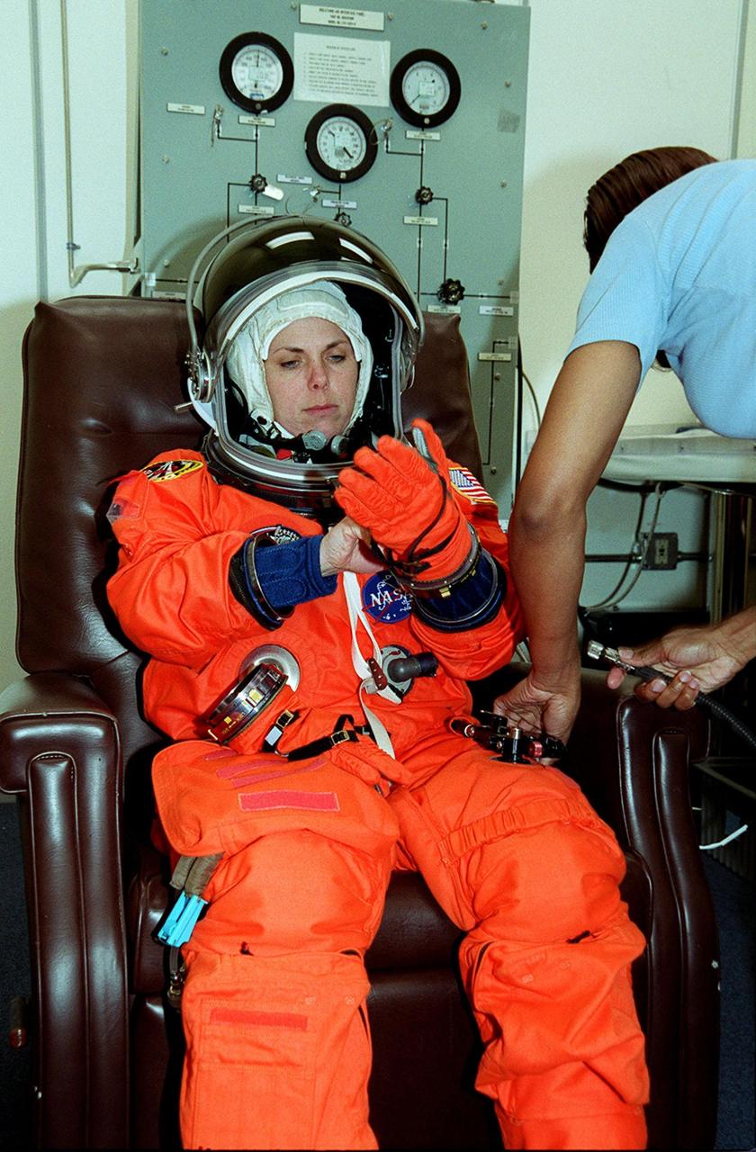 During pre-launch preparations in the Operations and Checkout Building, STS-101 Mission Specialist Mary Ellen Weber adjusts her glove during suit check. Mission STS-101 will take the crew to the International Space Station to deliver logistics and supplies, plus prepare the Station for the arrival of the Zvezda Service Module, expected to be launched by Russia in July 2000. The crew will conduct one space walk to perform maintenance on the Space Station as well. This will be the third assembly flight for the Space Station. Launch is targeted for April 24 at about 4:15 p.m. EDT from Launch Pad 39A
