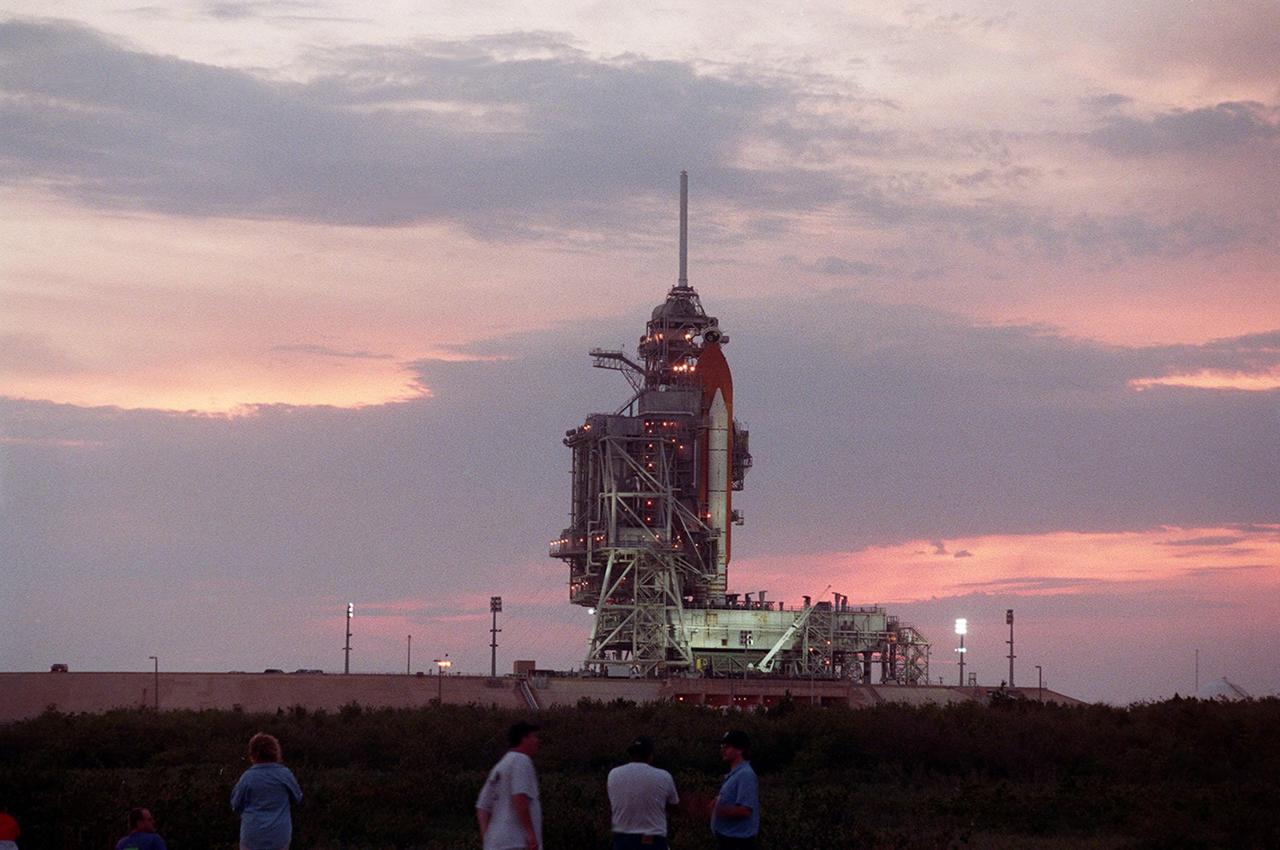 KENNEDY SPACE CENTER, Fla. -- The rosy-streaked clouds from a setting sun provide a dramatic backdrop for Space Shuttle Atlantis on Launch Pad 39A. Spectators (bottom) wait for the rollback of the Rotating Service Structure that covers the orbiter. In the photo only the orange external tank and white solid rocket booster are visible. Atlantis is targeted for liftoff at 4:15 p.m. EDT April 24 on mission STS-101. The mission will take the crew to the International Space Station to deliver logistics and supplies and prepare the Station for the arrival of the Zvezda Service Module, expected to be launched by Russia in July 2000. Also, the crew will conduct one space walk. This will be the third assembly flight to the Space Station