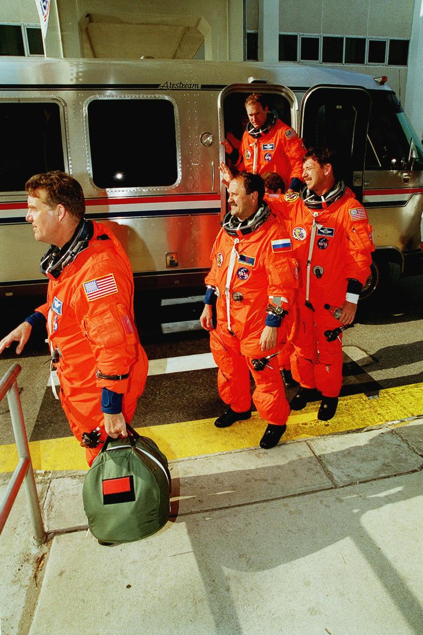 The STS-101 crew returns to the Operations and Checkout Building after the launch was scrubbed due to cross winds at the KSC Shuttle Landing Facility gusting above 20 knots. Flight rules require cross winds at the SLF to be no greater than 15 knots in case of a contingency Shuttle landing. Shown leaving the Astrovan are (left to right) Mission Specialists James S. Voss and Yury Usachev of Russia; Pilot Scott J. Horowitz; and Commander James D. Halsell Jr. in the doorway. Weather conditions will be reevaluated for another launch try on April 25. The mission will take the crew to the International Space Station to deliver logistics and supplies and to prepare the Station for the arrival of the Zvezda Service Module, expected to be launched by Russia in July 2000. Also, the crew will conduct one space walk. This will be the third assembly flight to the Space Station. The mission is expected to last about 10 days