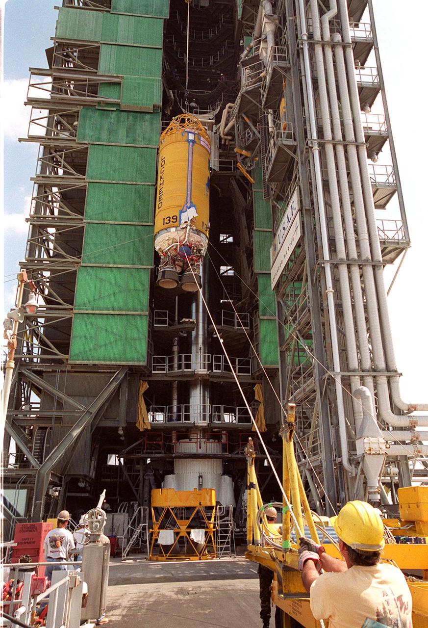 At Launch Pad 36A, Cape Canaveral Air Force Station, workers guide the ascent of a Centaur rocket up the launch tower where it will be mated with the lower stage Atlas IIA rocket already in the tower. The Lockheed-built Atlas IIA/Centaur rocket will launch the latest Tracking and Data Relay Satellite (TDRS) June 29 from CCAFS. The TDRS is one of three (labeled H, I and J) being built in the Hughes Space and Communications Company Integrated Satellite Factory in El Segundo, Calif. The new satellites will augment the TDRS system’s existing Sand Ku-band frequencies by adding Ka-band capability. TDRS will serve as the sole means of continuous, high-data-rate communication with the space shuttle, with the International Space Station upon its completion, and with dozens of unmanned scientific satellites in low earth orbit